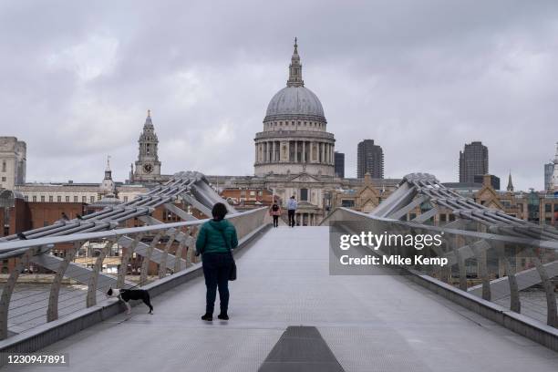 Woman walking her dog over a very quiet Millennium Bridge towards St Paul's Cathedral as the national coronavirus lockdown three continues on 28th...