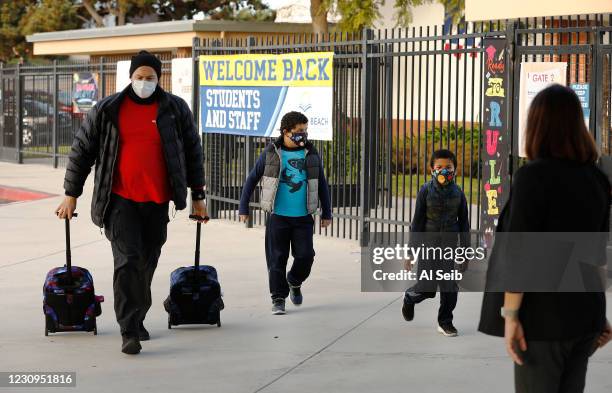 Father Luis Aracena helps his two first grade students Knoah Aracena, left and twin brother Kane Aracena with their backpacks as they arrive at Alta...