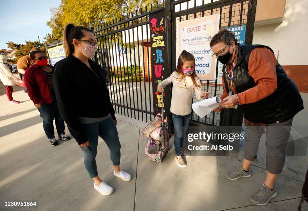 First grade student Braylen Coleman with her Mom Aja Coleman, left checks in with school staffer Gabrielle Flaum, right, as she arrives at Alta Vista...