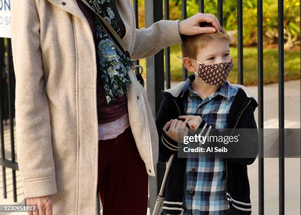 First grade student Felix Fuchs with his Mom Kate Fuchs waits to have his temperature taken when he arrives at Alta Vista Elementary School for the...