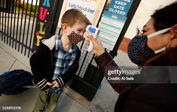 First grade student Felix Fuchs has his temperature taken by teachers aide Firoozeh Borjian as he arrives at Alta Vista Elementary School for the...