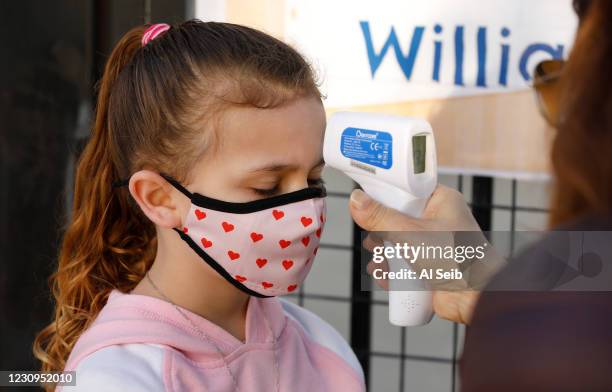 First grade student Gretchen Gray has her temperature taken by teachers aide Firoozeh Borjian as she arrives at Alta Vista Elementary School for the...