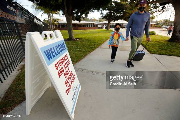 Father Alik Laddon helps his first grade student Caden Andino with his backpack as he arrives at Alta Vista Elementary School for the second day of...