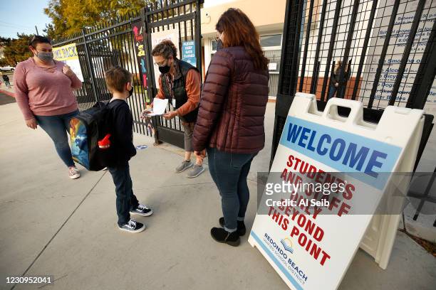 First grade student Brandon Blaco with his Mom Brandy Parras, left, checks in with Gabrielle Flaum and Firoozeh Borjian, right, before having his...
