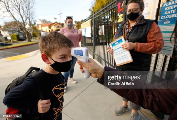 First grade student Brandon Blaco with his Mom Brandy Parras, left, has his temperature taken by Firoozeh Borjian, right, as he arrives at Alta Vista...