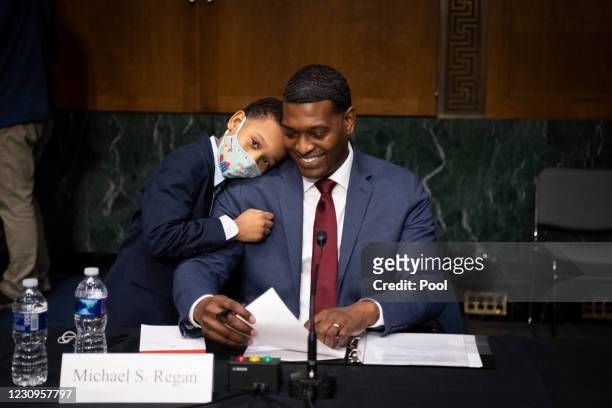 Nominee for Administrator of the Environmental Protection Agency Michael Regan is hugged by his son Matthew after his confirmation hearing before the...