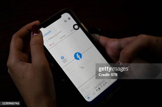 Woman uses her mobile phone to check Facebook in Yangon on February 4,2021 as Myanmar's generals ordered internet providers to restrict access to...