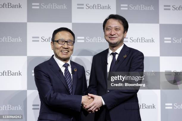 Junichi Miyakawa, incoming president and chief executive officer of SoftBank Corp., right, and Ken Miyauchi, incoming chairman, shake hands while...