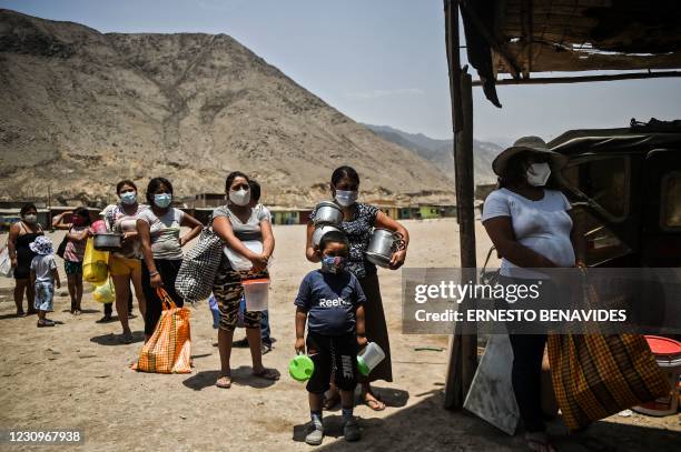 People keep safety distance as they wait to receive food at soup kitchen in Comas, in the northern outskirts of Lima on February 03 amid the new...