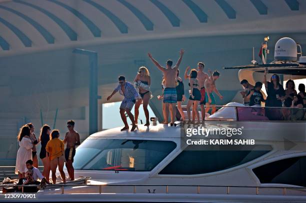 Youths party on a yacht in Dubai Creek, in the Gulf emirate, on February 4, 2021. - In Dubai, known for its luxury haunts and parties, expatriate...