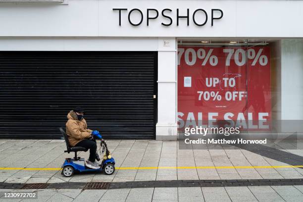 Man rides a mobility scooter past a closed Topshop store on Queen Street on February 4, 2021 in Cardiff, Wales. Wales went into a Level 4 lockdown...