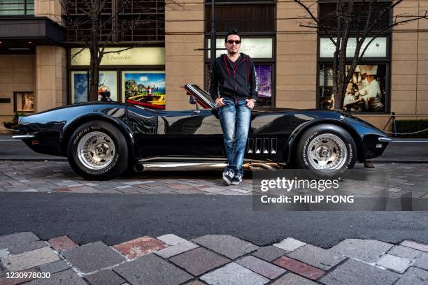 This picture taken on January 16, 2021 shows real estate and construction business owner Atsushi Hasegawa posing for a photo with a 1969 Chevrolet...