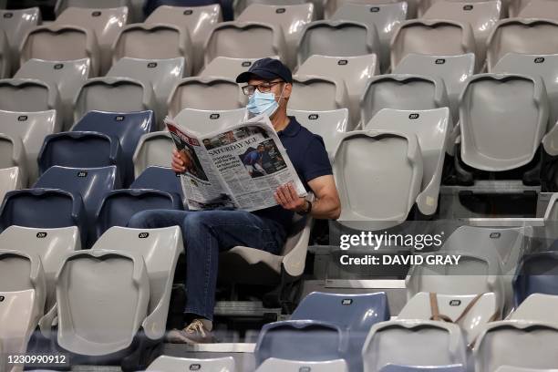 Spectator wearing face mask reads newspaper during the ATP Cup men's singles semi-final tennis match between Italy's Fabio Fognini and Spain's Pablo...