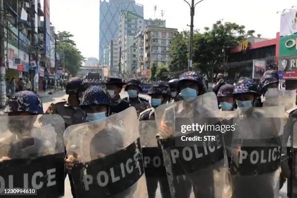 Screengrab taken from an AFPTV video shows police holding riot shields as protesters gather during a demonstration against the military coup in...