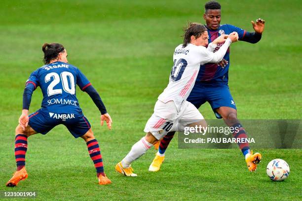 Huesca's Spanish midfielder Jaime Seoane and Huesca's Ivorian midfielder Idrissa Doumbia challenge Real Madrid's Croatian midfielder Luka Modric...