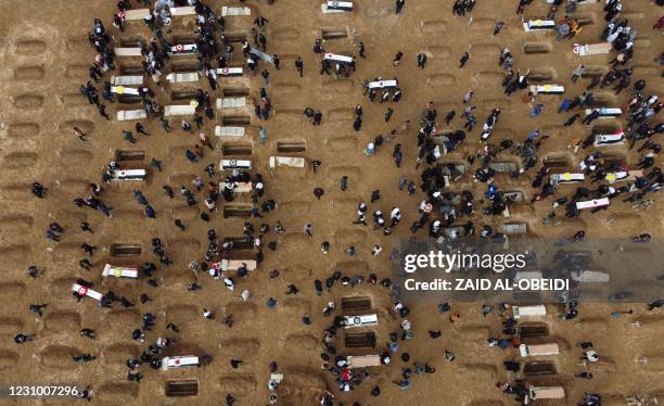 An aerial picture shows mourners gathering around gravesites during a mass funeral for Yazidi victims of the Islamic State group in the northern...