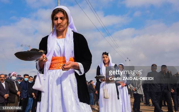 Women burn incense in a procession during a mass funeral for Yazidi victims of the Islamic State group in the northern Iraqi village of Kojo in...