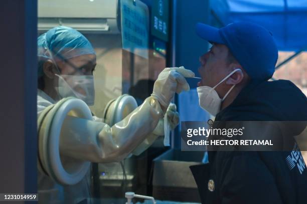 Health worker takes a swab sample from a man to test for the COVID-19 coronavirus at a hospital in Wuhan, China's central Hubei province on February...