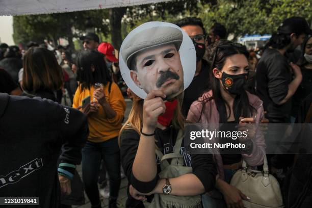 Female protester lifts a mask of Chokri Belaid as she took part in a rally held on avenue Habib Bourguiba in the capital Tunis in commemoration of...