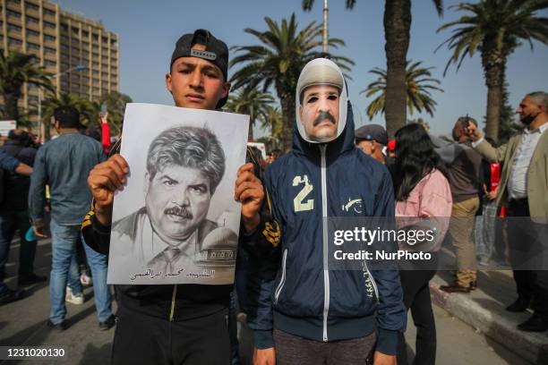 Young protester wears a mask of Chokri Belaid as another holds a portrait of Mohamed Brahmi during a rally held in the capital Tunis in commemoration...