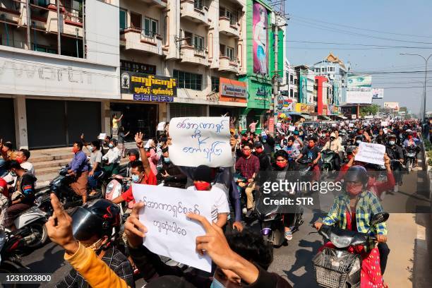 Protesters hold posters during a demonstration against the military coup near the royal palace in Mandalay on February 7, 2021. - Tens of thousands...