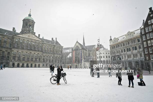 Pedestrians walk on a snow covered Dam Square in Amsterdam, on February 7, 2021. / Netherlands OUT