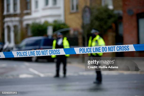 Metropolitan Police officers standing behind a police cordon at the scene of a stabbing at Willesden Lane on February 7, 2021 in London, England....