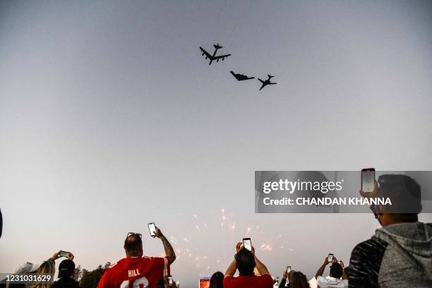 Football fans watch US Air Force strategic bombers B-52H Stratofortress, B-2 Spirit and B-1B Lancer flyover as they gather outside of the Raymond...