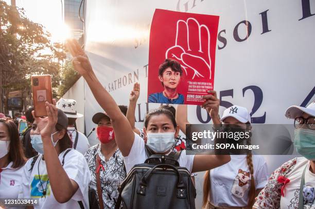 Protester wearing face mask makes three finger salute while holding a portrait of Aung San Suu Kyi during the demonstration. Myanmar protesters rally...