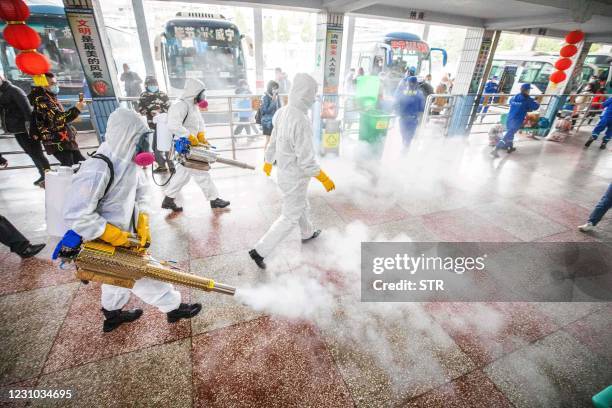 This photo taken on February 7, 2021 shows workers disinfecting a long distance bus station in Bijie, in China's southwest Guizhou province, as...