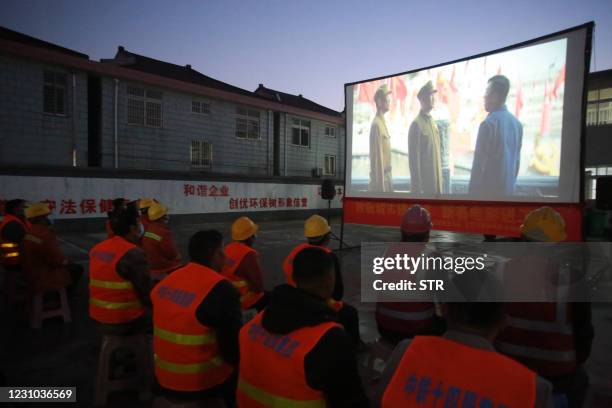 This photo taken on February 6, 2021 shows migrant workers watching a free outdoor movie provided by the Hanjiang District Government in Yangzhou, in...