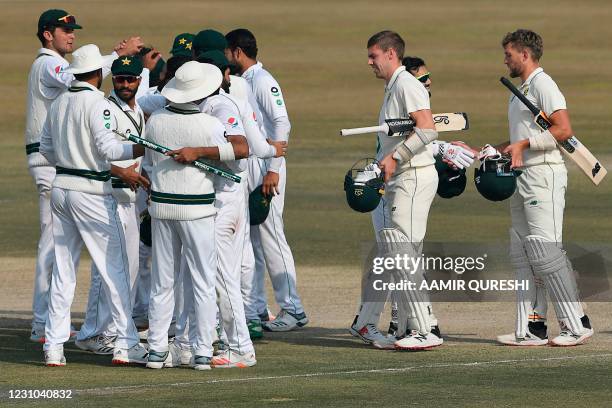 Pakistan's players celebrate after winning the Test series as South Africa's Anrich Nortje and Wiaan Mulder look on during the fifth and final day of...