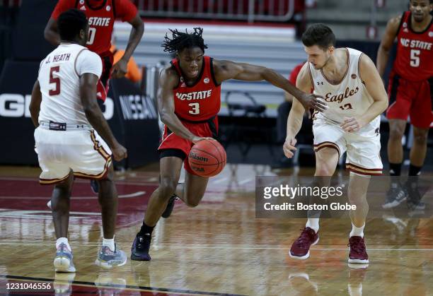 State player Cam Hayes drives ball down court , against Boston College players Jay Heath, left, and Luka Kraljevic, right. The Boston College Eagles...