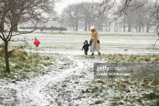 Woman and child walk through a snow covered edge of Wastead Park in East London. Heavy snow and ice has brought disruption to parts of the UK, with...