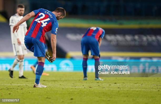 Crystal Palace's English defender Gary Cahill picks mud fromthe studs of his boots after the English Premier League football match between Leeds...