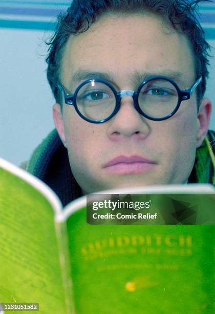 Heath Ledger, wearing Harry Potter glasses and reading "Quidditch through the Ages" that was sold in support of Red Nose Day 2001.