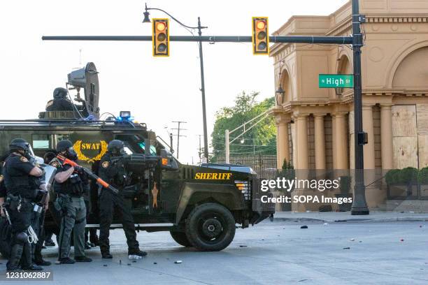 Ohio SWAT officer aims less-lethal launcher at the protesters on North High St while taking cover behind an armoured SWAT vehicle during the...