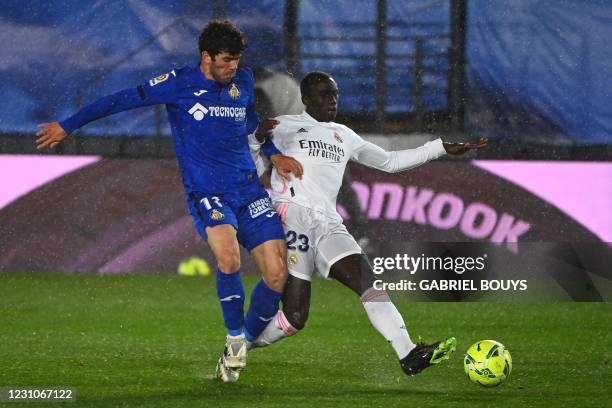 Getafe's Spanish midfielder Carles Alena challenges Real Madrid's French defender Ferland Mendy during the Spanish league football match between Real...