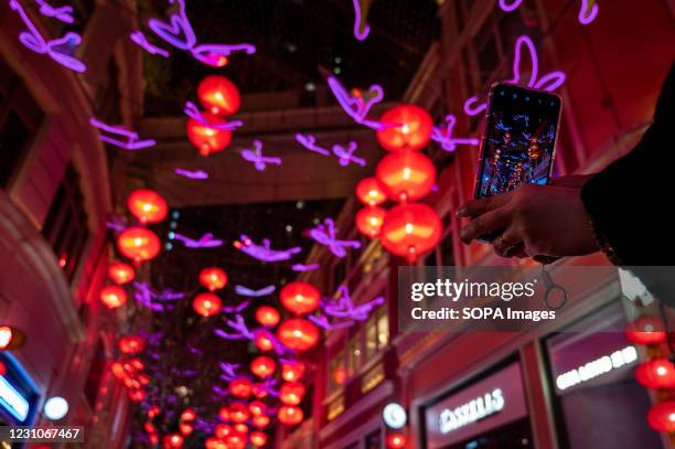 Woman uses her smartphone to take photos of hundreds of red lanterns hanged from the ceiling at Lee Tung Avenue in Hong Kong to celebrate the Chinese...