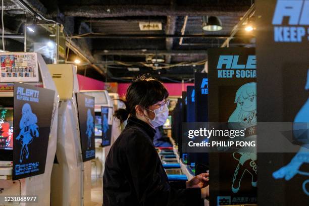 This picture taken on January 26, 2021 shows a woman playing a game at the Mikado game centre in the Shinjuku district of Tokyo. - Bright, noisy game...