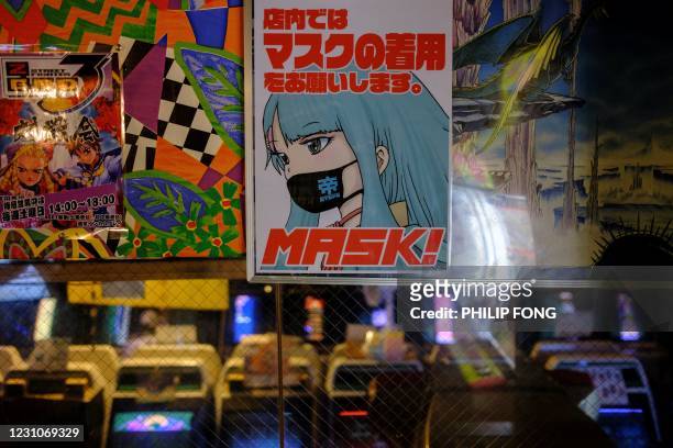 This picture taken on January 26, 2021 shows posters asking people to wear face masks at the Mikado game centre in the Shinjuku district of Tokyo. -...