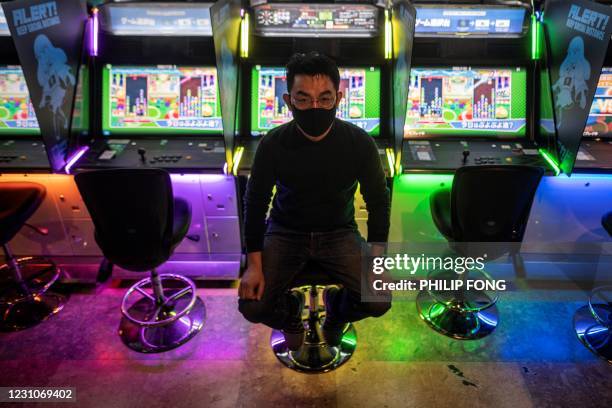 This picture taken on January 26, 2021 shows Yasushi Fukamachi, a manager at the Mikado game centre, posing in front of arcade game machines...