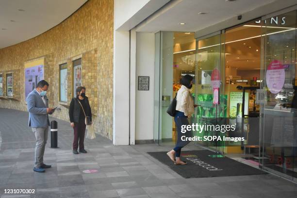 People wearing face masks line up outside a Liverpool store. As part of the "Activate without Risking" program, Shopping Malls and Department Stores...