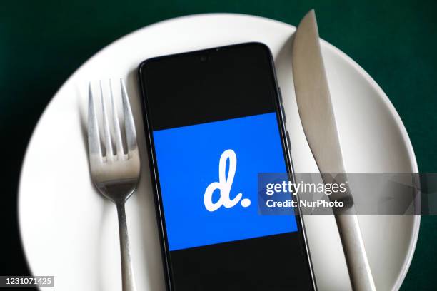 Delivery.com app logo is displayed on a mobile phone screen photographed for illustration on a plate and with cutlery. Krakow, Poland on February 9,...