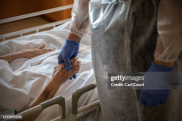 Hospital Director, Doctor Yutaka Kobayashi, holds the hand of a 94-year-old coronavirus patient on a coronavirus ward at Sakura General Hospital on...
