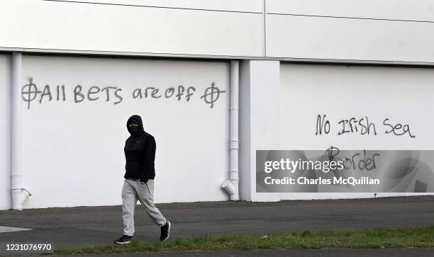 Man walks past threatening loyalist graffiti aimed at port staff on February 10, 2021 in Larne, Northern Ireland. Port inspection staff have returned...