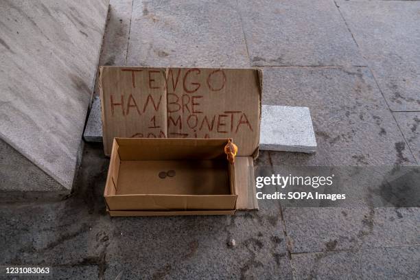 Placard saying I'm hungry a coin thanks is seen next to a cardboard box to collect coins in the central commercial avenue of Passeig de Gràcia. The...