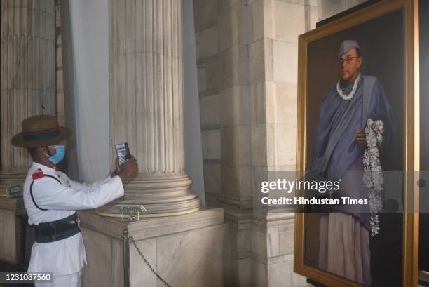 Member of Indian Military Band takes a photograph of a portrait hung during a multimedia exhibition to celebrate the 125th birth anniversary of...