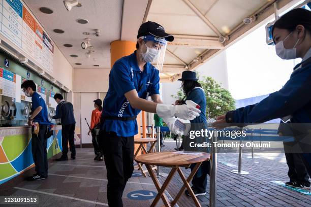 An employee playing the role of a customer uses a hand sanitizer during a training session for employees held ahead of the reopening of the...