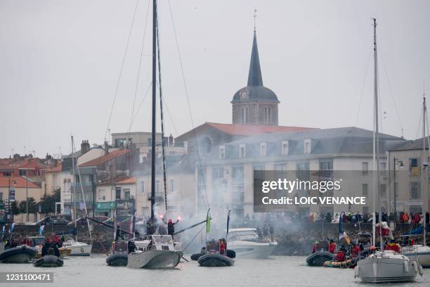 Japanese skipper Kojiro Shiraishi brandishes flares as he celebrates aboard his Imoca 60 monohull "DMG Mori Global One" after crossing the finish...